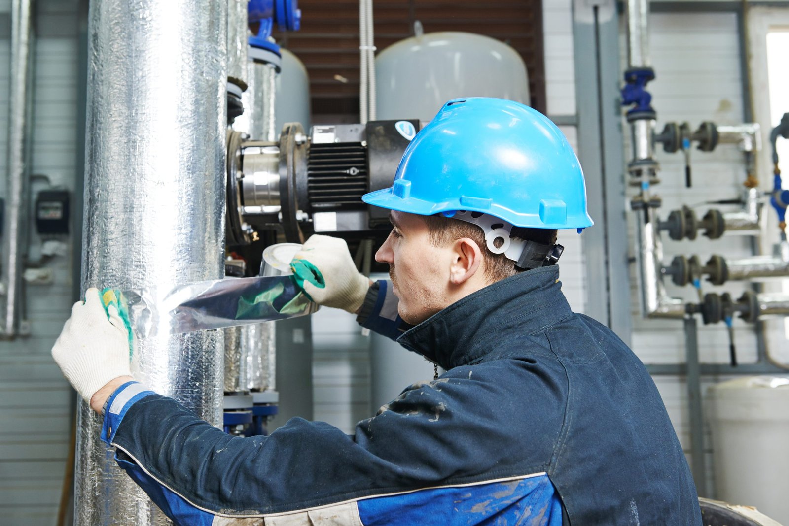 industrial construction worker at boiler room pipe heat insulation work